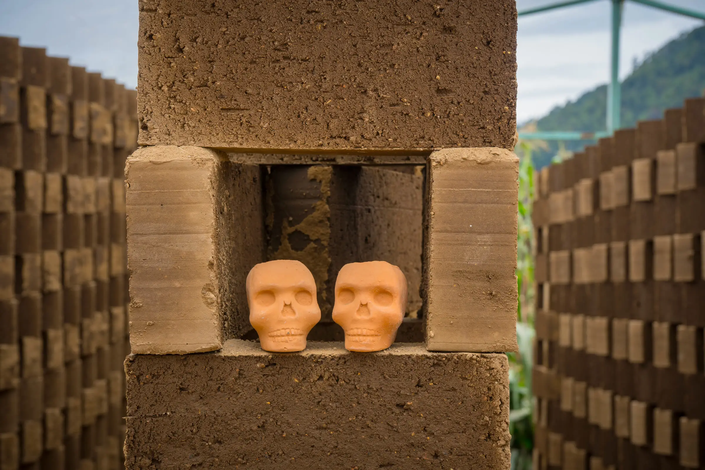 Calaveras de barro asomando entre los huecos de un muro de ladrillo