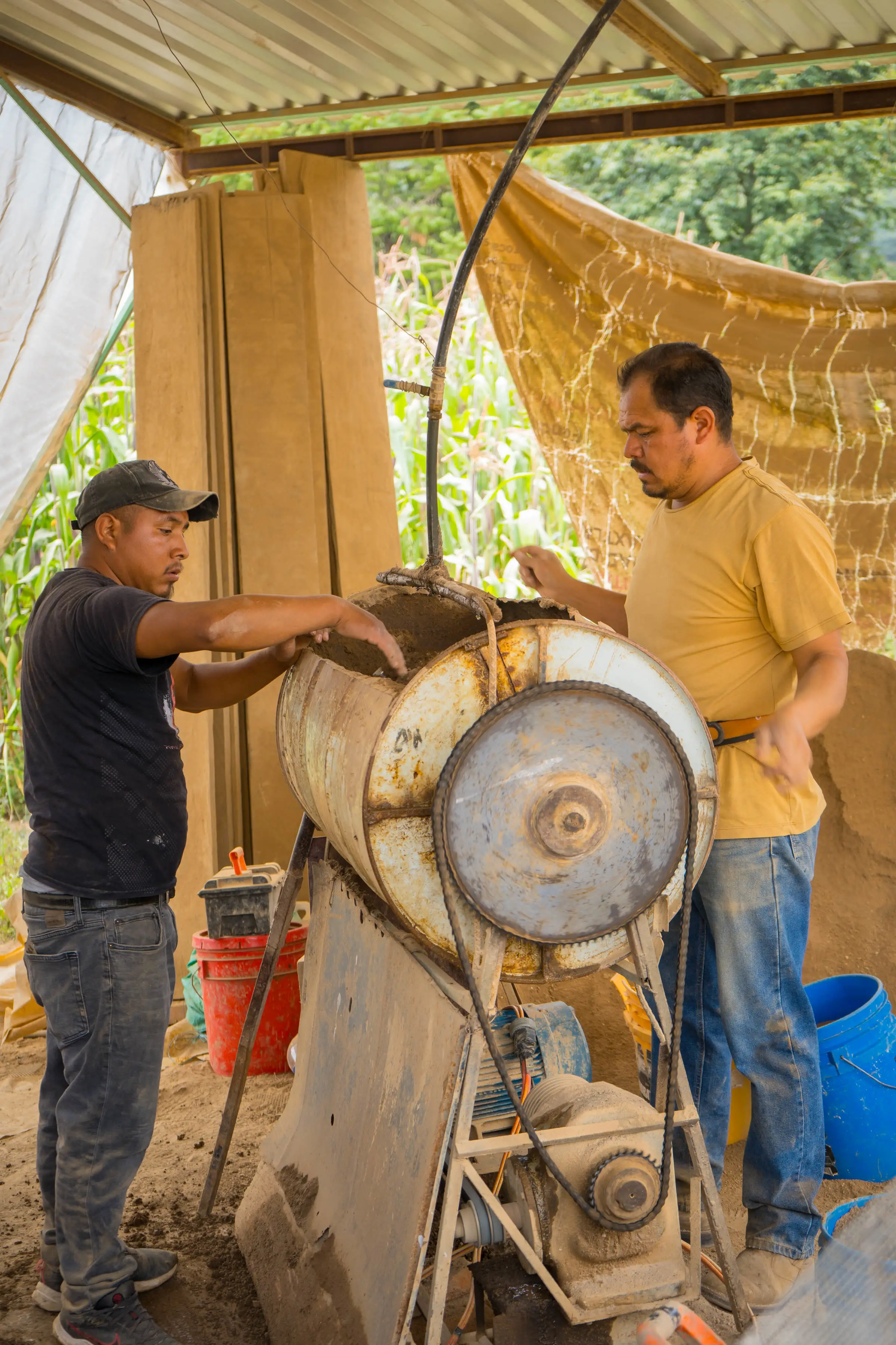Dos trabajadores amasando barro en la mezcladora del taller